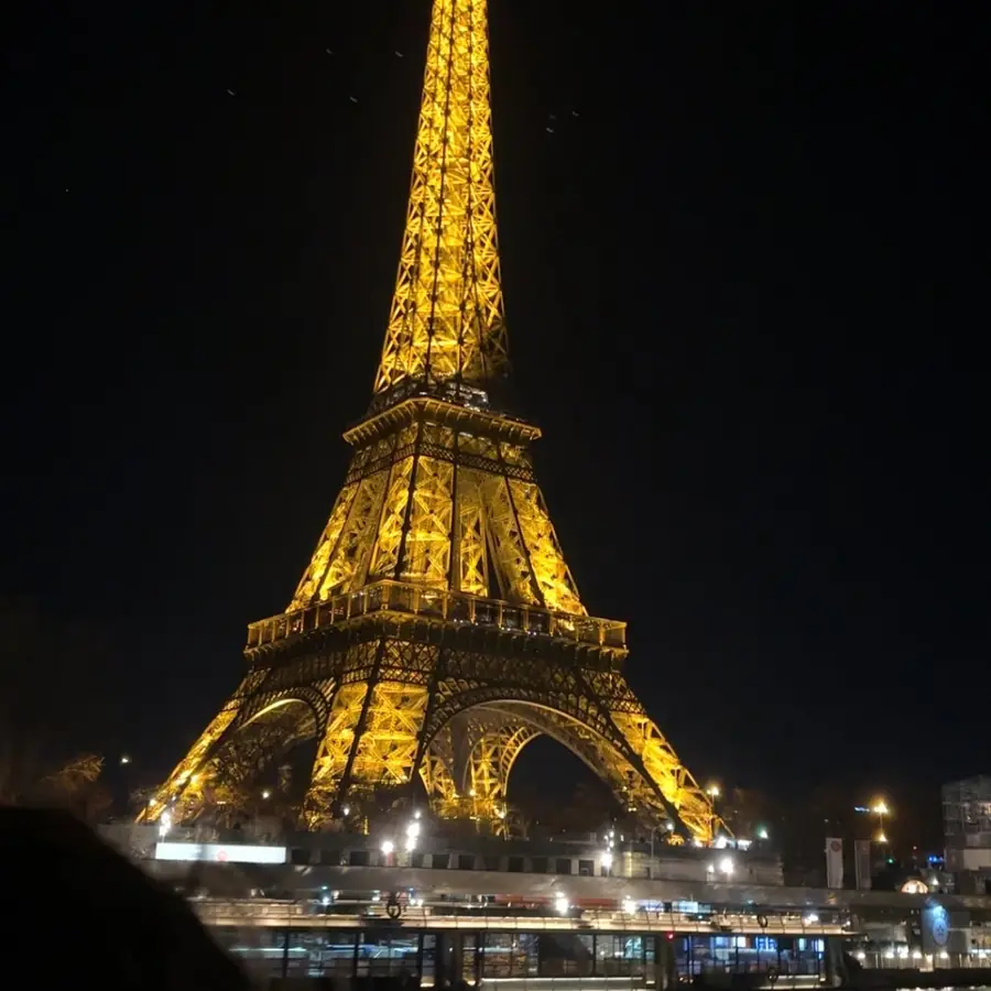 The Eiffel Tower lit up over the Seine, shot from the water
