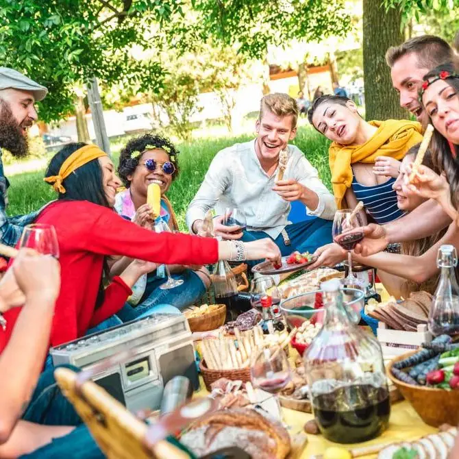 A group of friends around a long picnic table on the grass